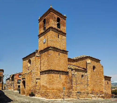 Iglesia de Santa María en Mélida, Navarra, con torre de reloj y campanario.
