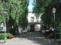 Schlossplatz in Vinalesa mit Bäumen, Laternen und einem Gebäude im Hintergrund.