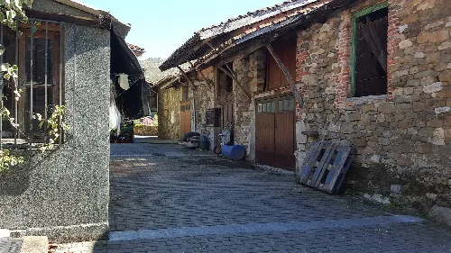 Calles de un pueblo con casas de piedra y un camino pavimentado en Sobrescobio.