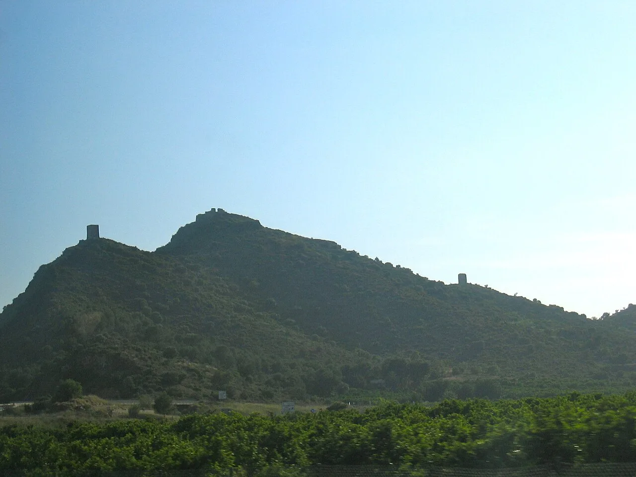 View of Almenara Castle from the north, with walls and towers on the hilltop.