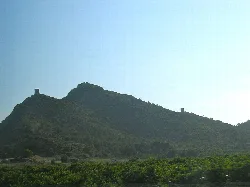 View of Almenara Castle from the north, with walls and towers on the hilltop.