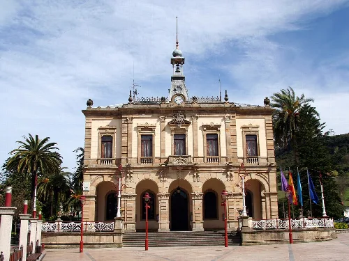 Edificio del ayuntamiento con columnas y banderas en Villaviciosa.