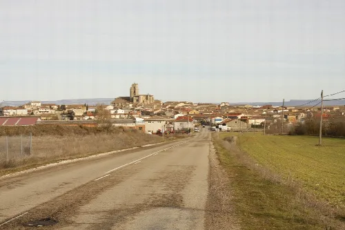 Rural road with view of Sasamón and its church in the background.