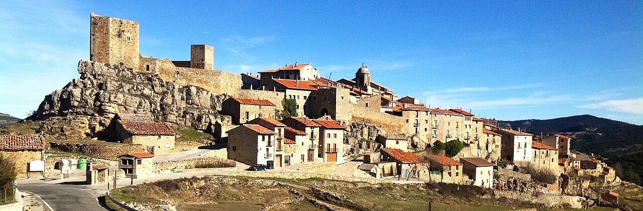 Panoramic view of Puertomingalvo with houses and castle on the hill.