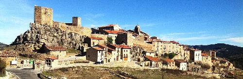 Panoramablick auf Puertomingalvo mit Häusern und Burg auf dem Hügel.