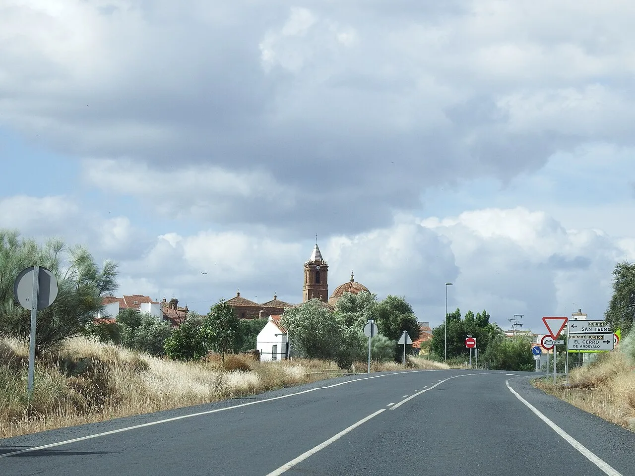 Carretera con señal de tráfico y iglesia en el fondo en El Cerro de Andévalo.