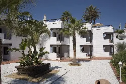 Edificio blanco de varias plantas con terrazas y palmeras en Mojácar.