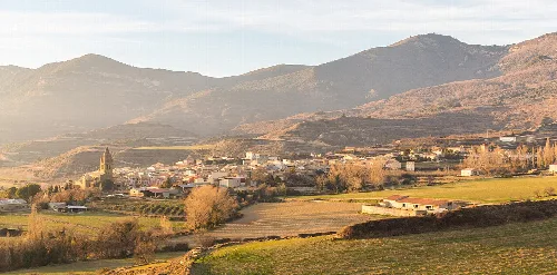 Blick auf ein Dorf mit Bergen und Feldern in Huesca, Spanien.