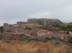 Steinhäuser und ein großer Felsen im Hintergrund in Miño de Medinaceli