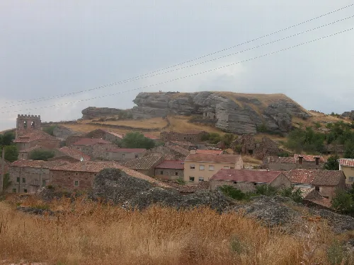 Steinhäuser und ein großer Felsen im Hintergrund in Miño de Medinaceli