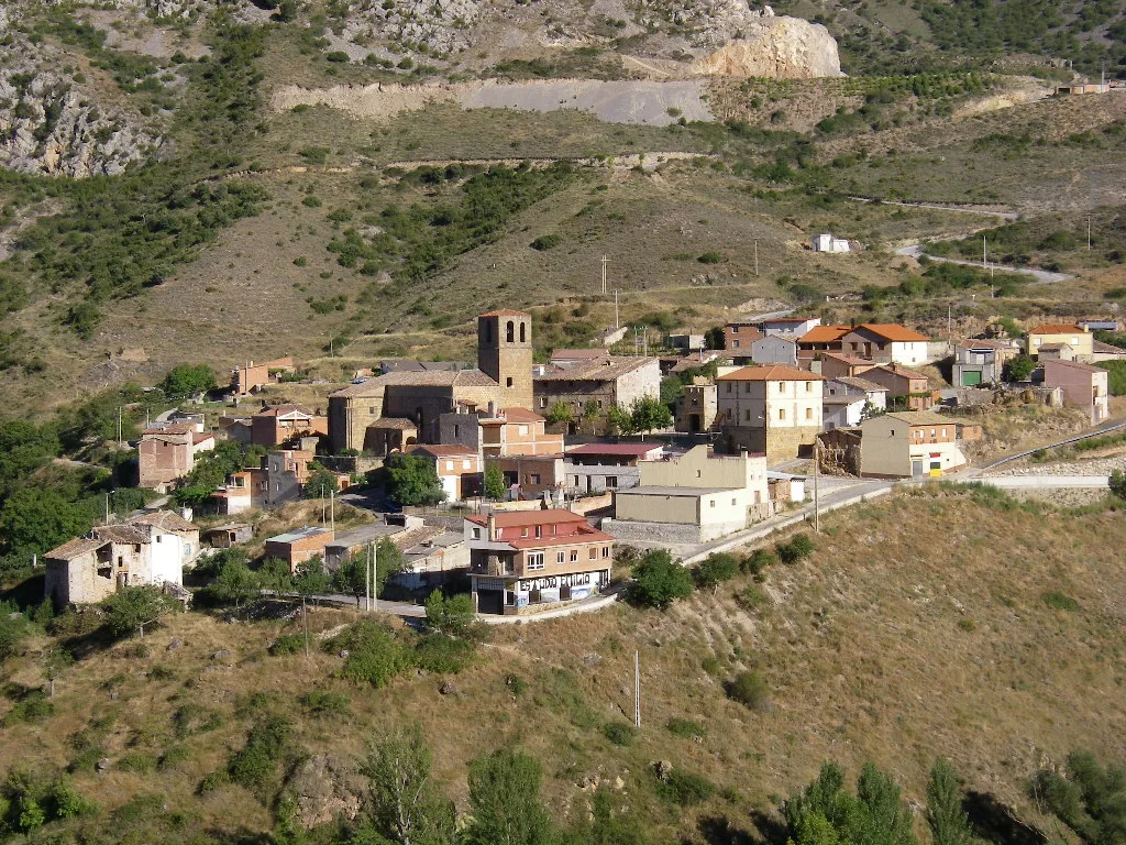 Vista panorámica de un pueblo en una ladera montañosa con casas y una iglesia.