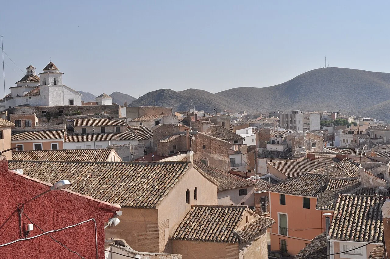 Casas y calles en Hellín con colinas en el fondo.