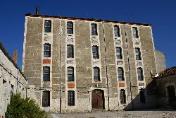 Gebäude der alten Mühle mit mehreren Stockwerken und ausgerichteten Fenstern.
