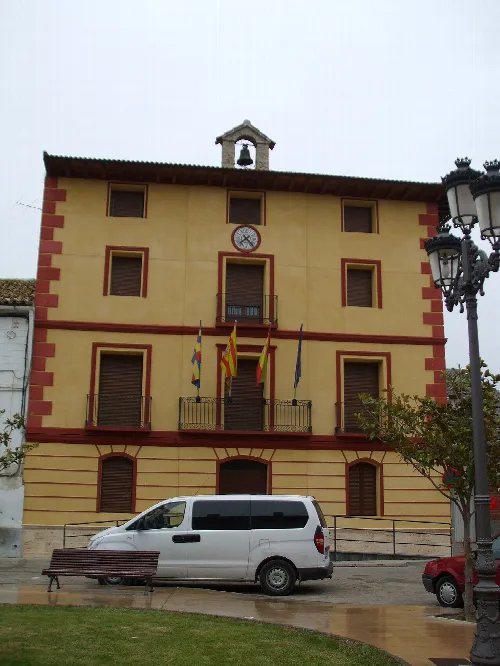 Town hall building with flags and clock on the facade.