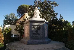 Statue of Santa Vicenta María on a pedestal in a square surrounded by trees and buildings.