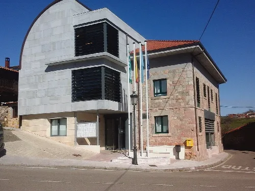 Edificio del ayuntamiento de Las Regueras con estructura moderna y fachada de piedra.