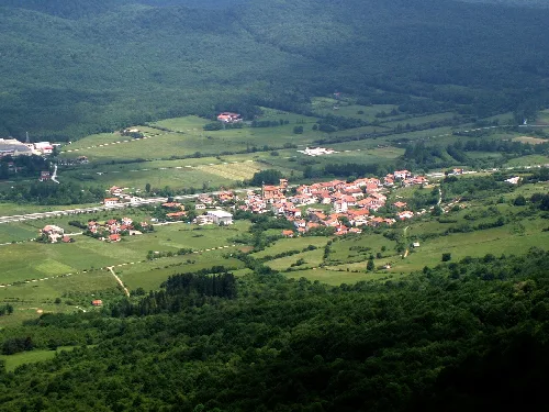 Vista panorámica de un pueblo en un valle rodeado de montañas y vegetación.