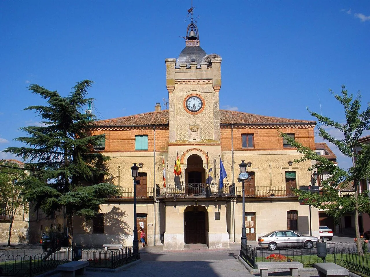 Edificio del ayuntamiento con reloj y banderas en la fachada.