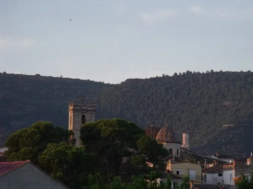 Panoramablick auf Bélgida mit Turm, Häusern und Bergen im Hintergrund.