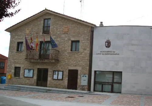 Stone building with flags on the balcony and town hall sign.