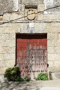Puerta de madera envejecida con detalles de hierro en un edificio antiguo.