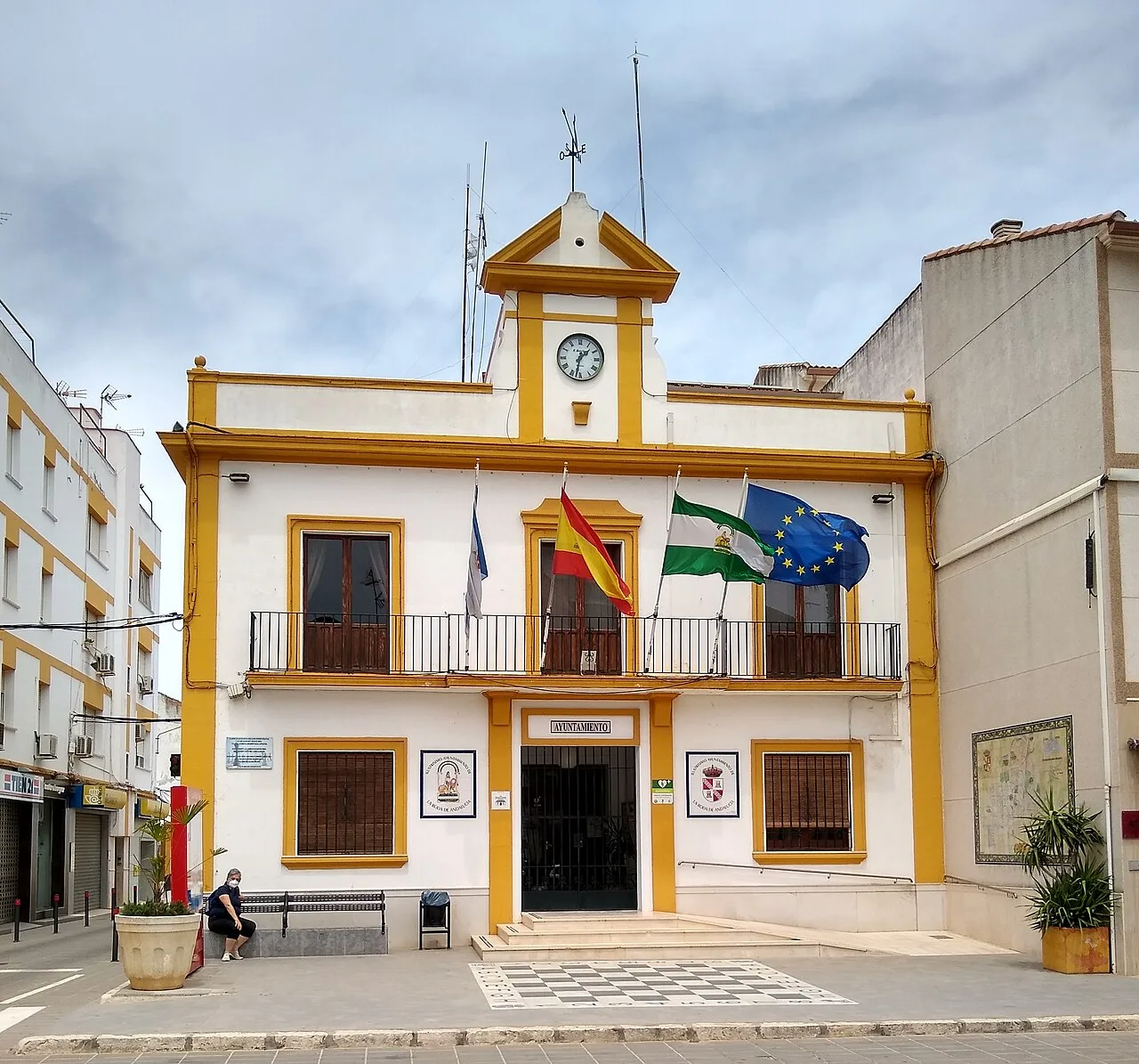 Edificio del ayuntamiento de La Roda de Andalucía con banderas y reloj en la fachada.