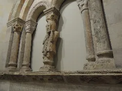 Romanesque twin window with columns and a central figure in San Miguel's tower.