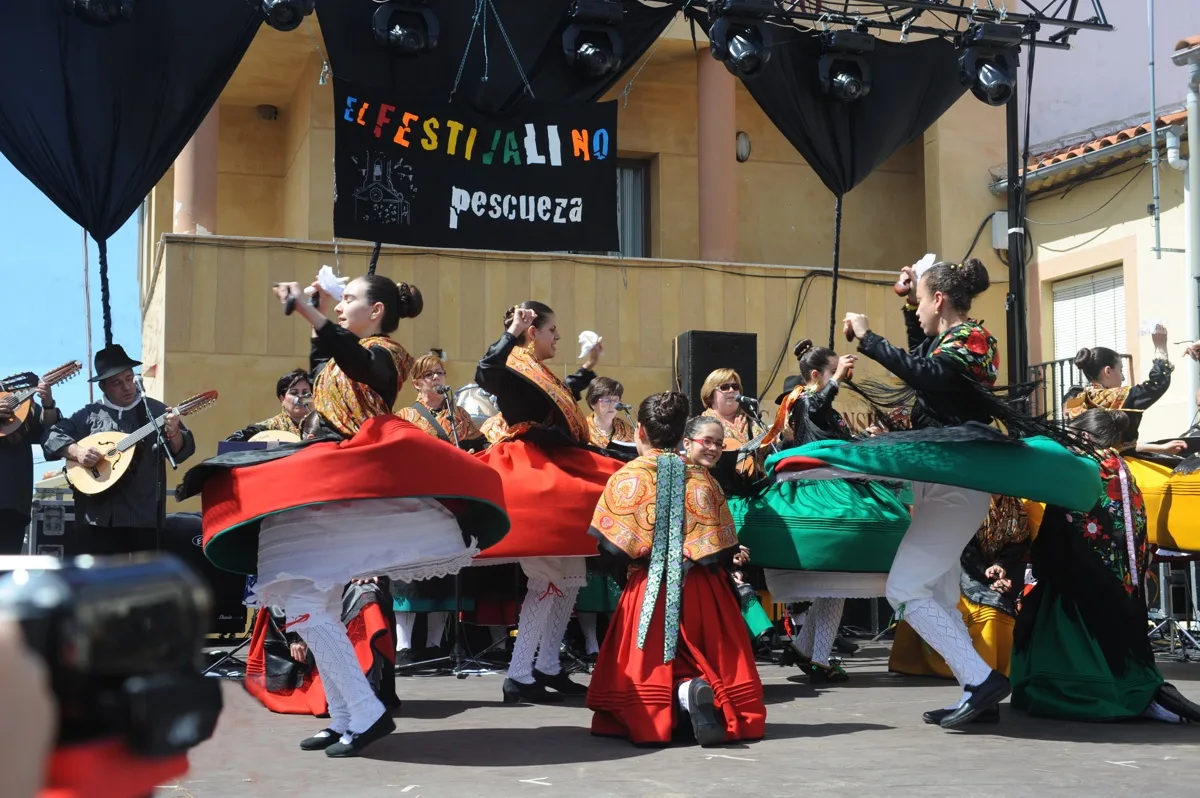 Bailarinas con trajes tradicionales bailando en un escenario en Pescueza.