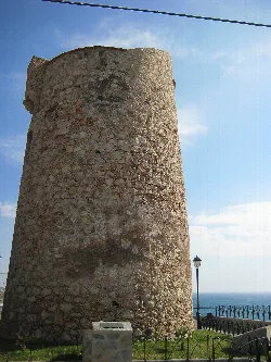 Runder Steinturm mit Meer und Himmel im Hintergrund.