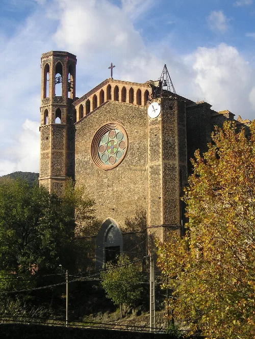 Steinige Kirche mit Turm und Rosettenfenster in Sant Joan les Fonts.