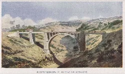 Iron bridge with an arch in a valley surrounded by green hills.