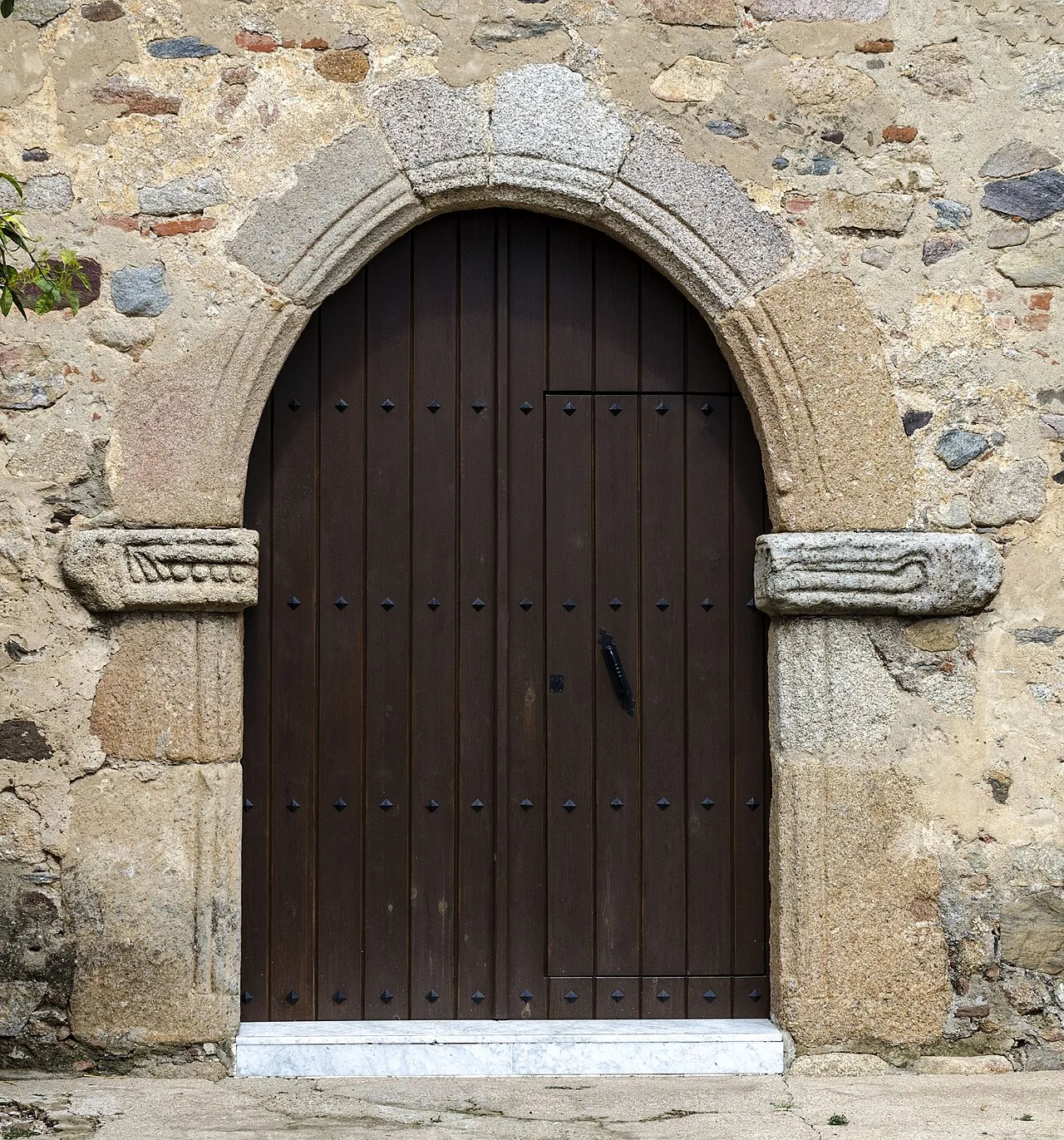 Puerta lateral de la Iglesia Parroquial de Trujillanos, municipio de Badajoz, España. Se observan dos piezas de piedra labrada de origen visigodo en cada una de sus jambas laterales.