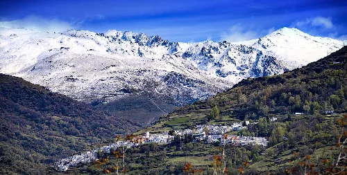 Weißes Dorf mit schneebedeckten Bergen im Hintergrund.