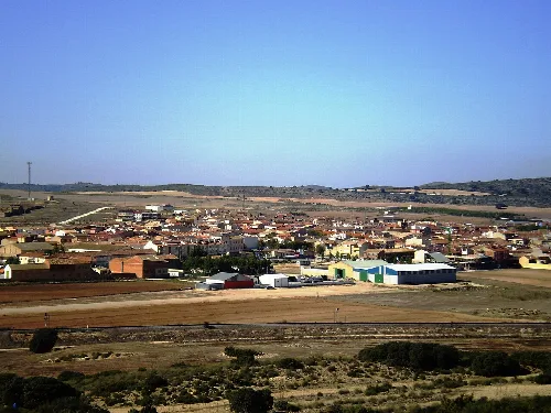Vista de Pozo Cañada con edificios y campos en el fondo.