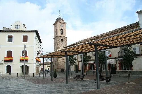 Square with canopy, benches, and church in Belvís de la Jara.