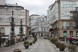 Straße in Betanzos mit alten Gebäuden und Topfpflanzen.