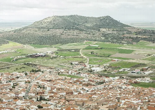 Luftaufnahme eines Dorfes mit einem Berg im Hintergrund.