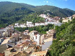 Vista de casas blancas y calles en Villafamés, en un entorno de montañas verdes.