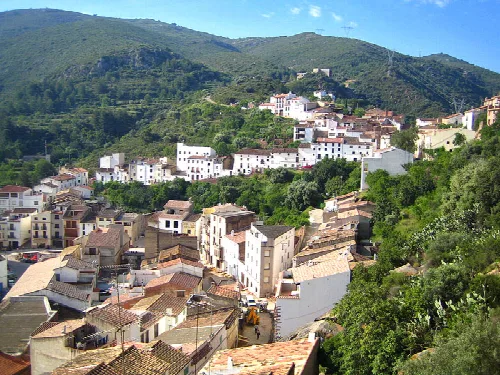 Vista de casas blancas y calles en Villafamés, en un entorno de montañas verdes.