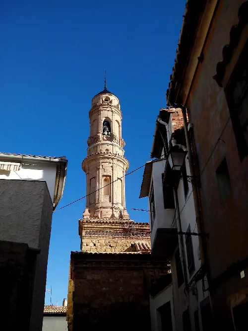 Turm der Salvador-Kirche in Ariño mit klarem blauen Himmel.