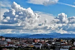 Vista de la villa de Melide con casas y montañas en el fondo.