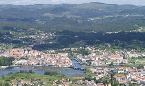 Panoramic view of Noia with river and city buildings.