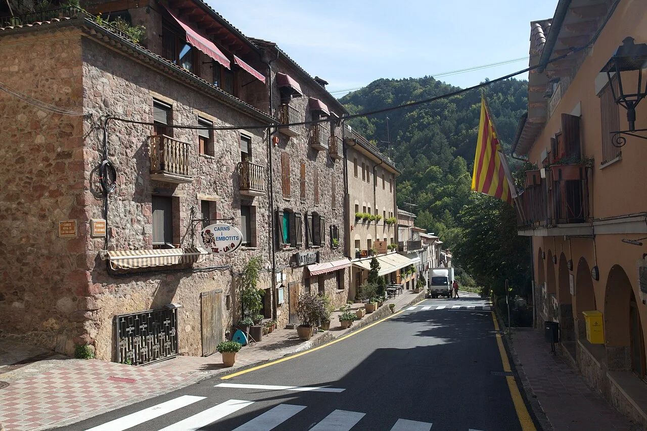 Straßen von Ogassa mit Steinhäusern und katalanischer Flagge.