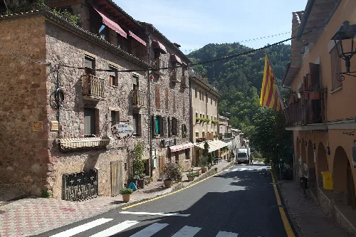 Straßen von Ogassa mit Steinhäusern und katalanischer Flagge.