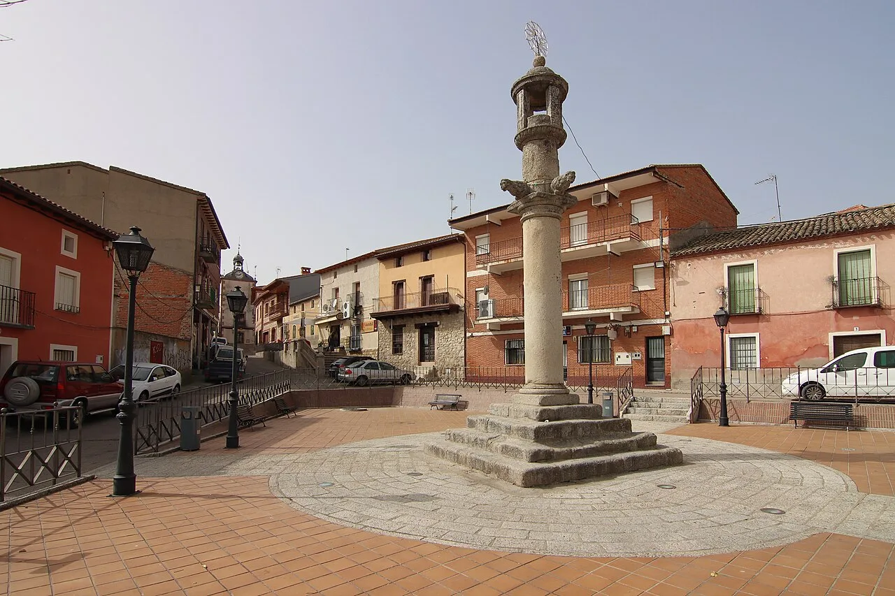 Fountain in Plaza de la Constitución in Nombela with nearby buildings and streets.