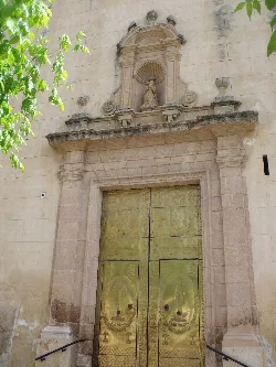 Fachada de una iglesia con puertas doradas y detalles en piedra.