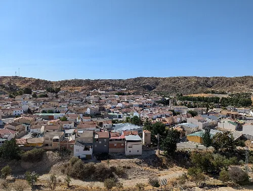 Panoramablick auf Alamedilla von einem Aussichtspunkt, mit Häusern und Hügeln im Hintergrund.