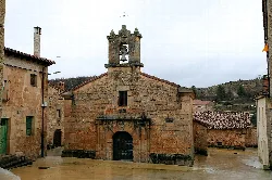 Stone chapel facade with bell tower and arched door in Moncalvillo.