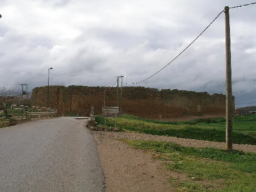 Vista del castillo y un camino con postes de electricidad.