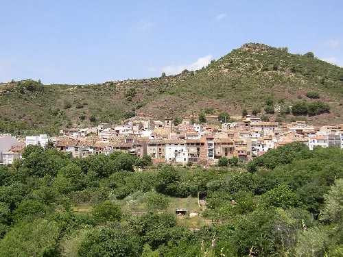 Vista panorámica de un pueblo en una ladera con montañas al fondo.